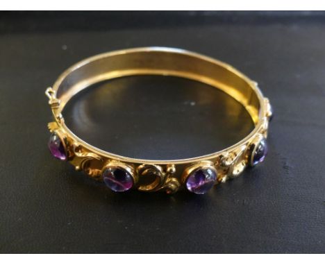 A 1950s 18ct gold synthetic colour change sapphire bangle, the synthetic colour change sapphire cabochons with scrolling spac