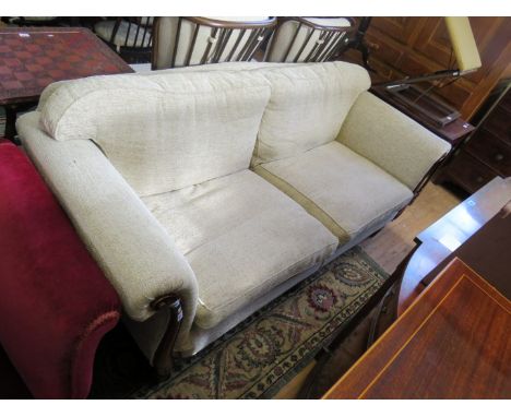 A modern three seater sofa in the Victorian style with show wood frame and oatmeal upholstery 