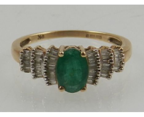 A 9 carat yellow gold, emerald, and baguette cut diamond ring. 