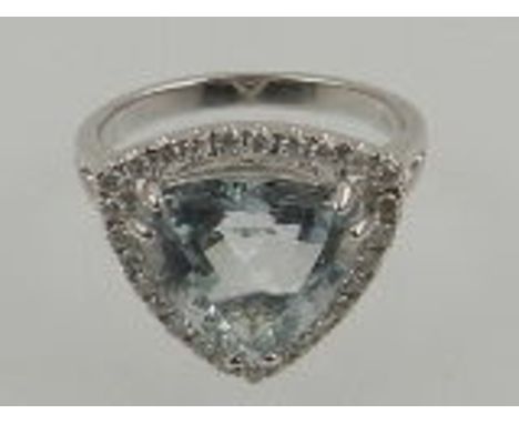 An 18 carat white gold, diamond, and aquamarine ring, set trillion cut aquamarine in an openwork diamond set mount. 