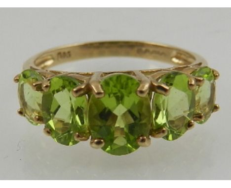 A 9 carat yellow gold and peridot graduated five stone ring. 