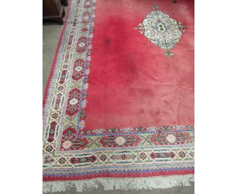 A large burgundy ground Oriental Carpet, with plain centre and decorative floral pattern border, 13'5" x 9'10". (1)