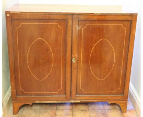 A Georgian period Irish mahogany Linen Press,  the plain top over two panel doors with oval inlaid decoration, on bracket fee