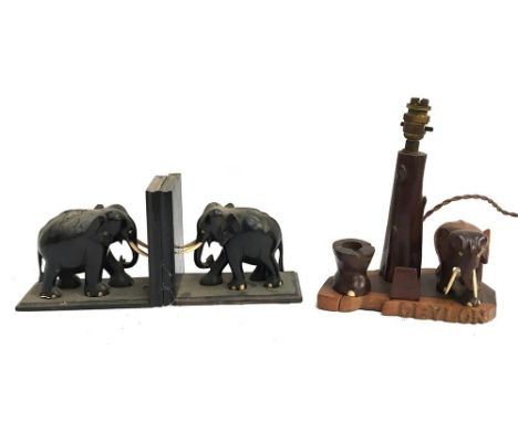 A pair of carved hardwood elephant bookends; wooden bookends in the form of cannons (af); together with a carved table lamp i