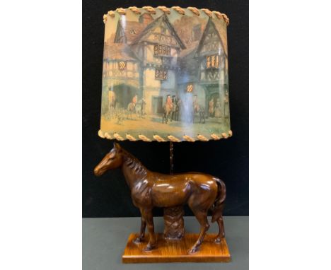 A novelty table lamp, the base with a horse, the shade with figures on horses outside a Tudor building, c.1960 