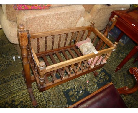 An early 20th c. Baby's Cradle in mixed woods and having turned detail supports and feet and bobbin turned detail to the side