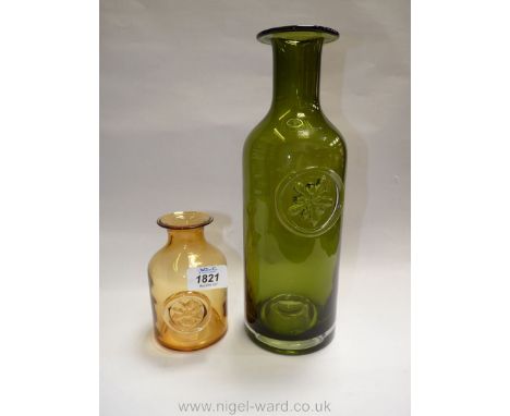 A Dartington glass bottle vase in bottle green with raised floral detail and another in light amber with similar design, sign