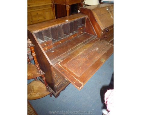 A profusely carved Oak Bureau probably mid-late 19th c., the slope revealing an interior with nine pigeon holes and six drawe