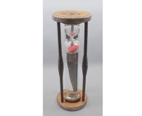 Clear glass egg-timer, in turned wooden frame, 17" high 