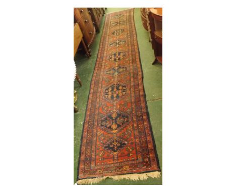 20th century wool floor runner carpet, decorated in reds and blues with central lozenges, approx 190" long  