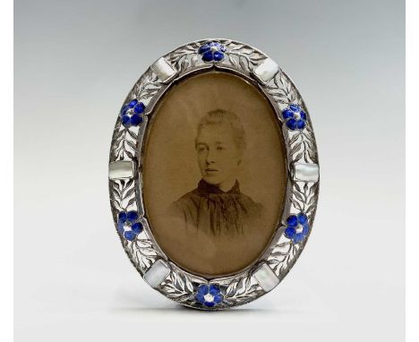 An Ella Naper (1886-1972) enamelled silver and mother of pearl oval frame, the broad border has six panels each is pierced wi