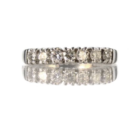 A diamond half eternity ring in 18ct white gold designed as a single row of seven round cut diamonds weighing approximately 0