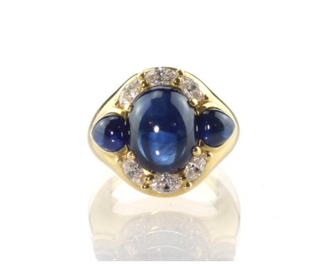 A sapphire and diamond dress ring in 18ct yellow gold the large oval cabochon blue sapphire weighing approximately 8.5cts, se