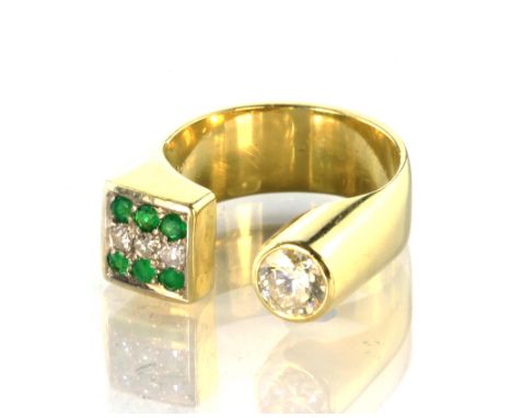 A modernist diamond and emerald dress ring in 18ct yellow gold, designed as an incomplete band, set at one end with a solitai