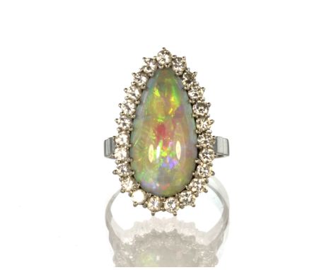 An opal and diamond cluster dress ring in 18ct white gold designed as an elongated tear drop shape opal cabochon surrounded b