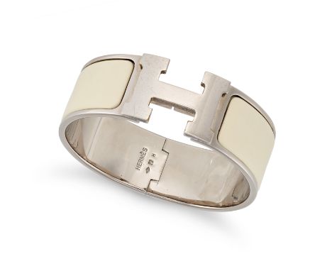 HERMÈS, A CLIC-CLAC H BANGLE, comprising an ‘H’ logo clasp, cream toned enamel, and palladium toned metal. 16.0cm inner circu
