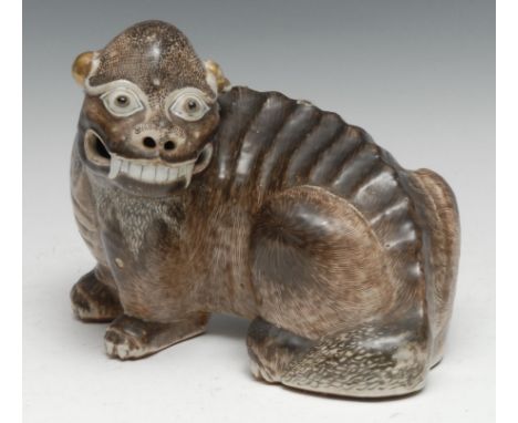 A Chinese porcelain model, of a Dog of Fo, typically modelled and picked-out in naturalistic tones, gilt ears, 22cm long, 19t