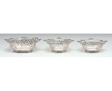 An Edwardian garniture of three shaped rectangular sweetmeat dishes, pierced leafy scroll borders, pierced bracket feet, 22cm