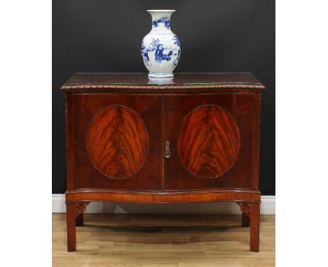 A Chippendale Revival mahogany serpentine side cabinet, gadrooned top above a pair of rectangular door centred by flame venee