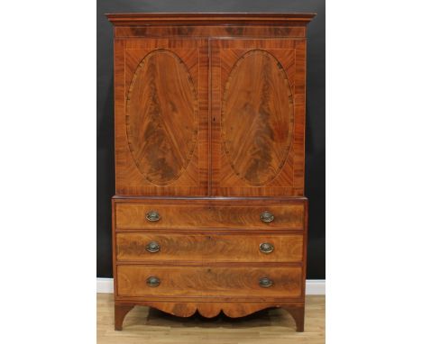 A 19th century mahogany linen press, outswept cornice above a pair of rosewood crossbanded oval panel doors enclosing two she
