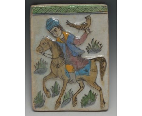 A Middle Eastern Islamic rectangular tile, moulded and painted in the typical Qajar manner with a falconer on horseback, 23cm
