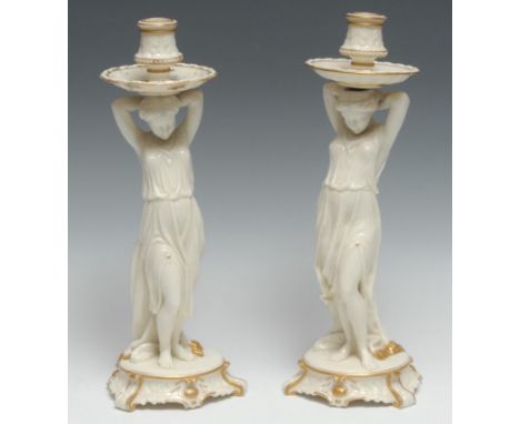 A pair of Royal Worcester  glazed parian figural candlesticks,  of young ladies holding sconces above their head, 32cm high, 