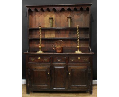 A 'George III' oak dresser, outswept cornice and shaped apron above two plate rack shelves, the projecting base with three fr