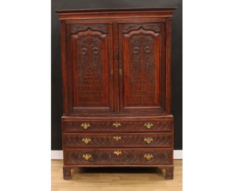 A 'George III' oak press cupboard, outswept cornice above a pair of panel doors, each carved with squamous scrolls and a pyra
