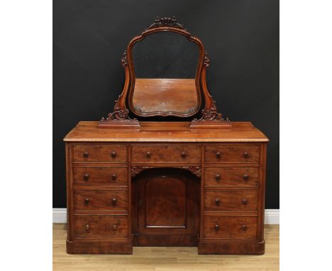 A Victorian mahogany dressing table, cartouche shaped mirror plate, serpentine supports carved with scrolls, leaves and a flo