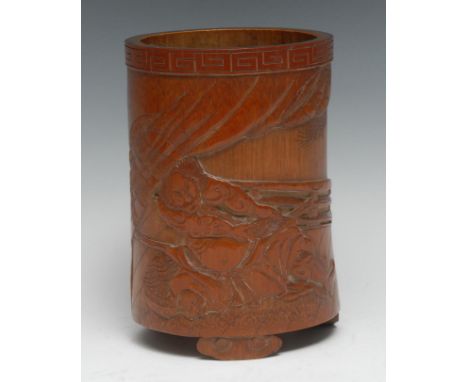 A Chinese bamboo bitong brush pot, carved in relief with two warriors, the curtained background incised with foliage, meander