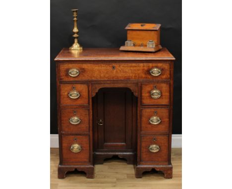 A George III oak kneehole desk, rectangular top with moulded edge above a long cockbeaded frieze drawer, the niche with a rec