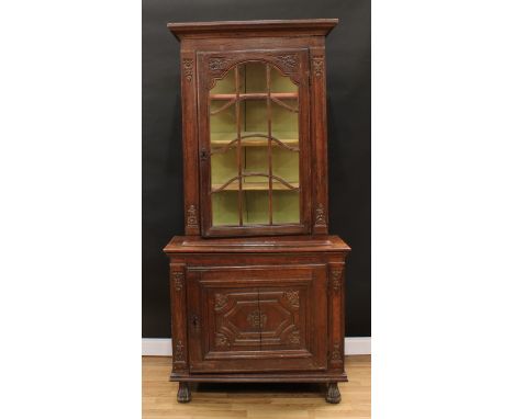 An 18th century Continental oak display cabinet, outswept cornice above an astragal glazed door enclosing three shelves, glaz