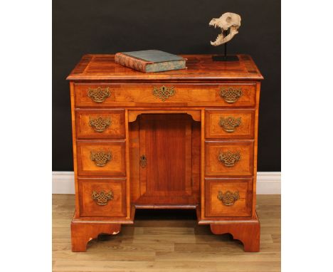 A George II Revival walnut kneehole desk, rectangular top with moulded edge above a long frieze drawer and a cupboard door to