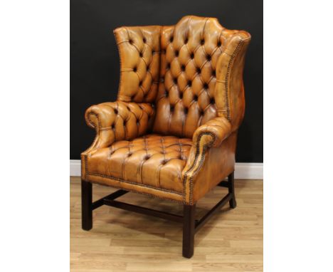 A George III design Chesterfield wingback armchair, studded stuffed-over deep button upholstery, square forelegs, rectangular