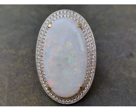A large opal &amp; diamond oval cluster ring, the four-claw set opal of flat cabochon form, measuring 32mm across, held above
