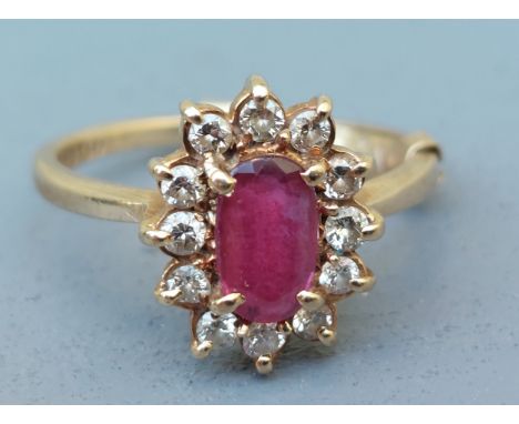 An oval ruby &amp; diamond cluster ring in 9ct gold.  Finger size K.