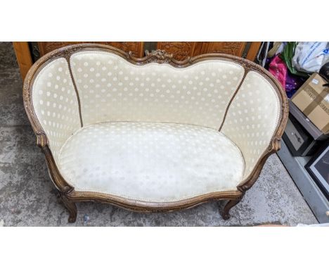 A French walnut matched three-piece salon suite upholstered in a cream floral fabric, the two seater sofa with carved decorat