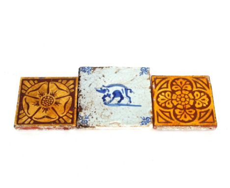 An 18th Century blue and white Dutch Delft tile with pig decoration, 13cm; and two other tiles, brown and yellow glazed with 