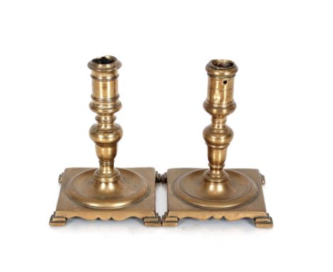 A good pair of 17th Century brass desk candlesticks of baluster form, raised on square bases and stepped bracket feet, 16cm h