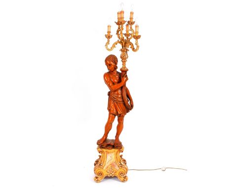 A pair of carved wooden Blackamoor type lamps, the figures holding gilded five light branches above them on Rococo style gild