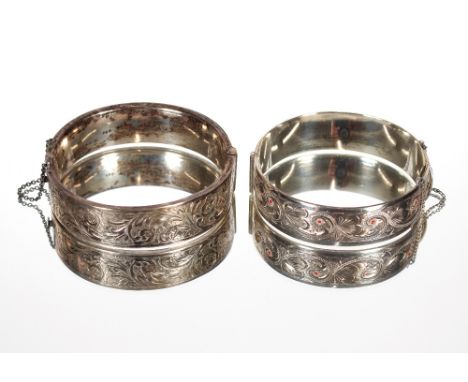 A Foliate engraved hinged silver bangle, inset with red semi-precious stones; and another foliate engraved silver bangle (2)