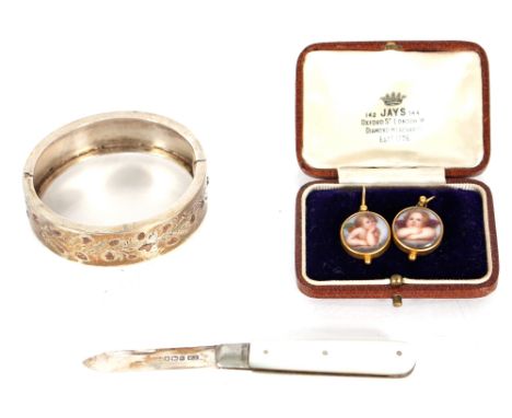 A pair of yellow metal hook ear-rings inset with porcelain panels of cherubs; a small silver and yellow metal inlaid snap ban
