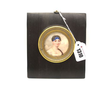 An Early XIX Century Portrait Miniature, painted on ivory, of a lady wearing a white dress with a blue ribbon in her hair, wi