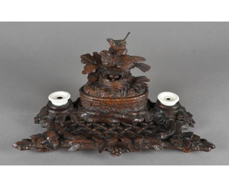 A Black Forest carved table top inkwell, modelled as a naturalistic oak tree with lattice work pen rest, two ceramic ink pots