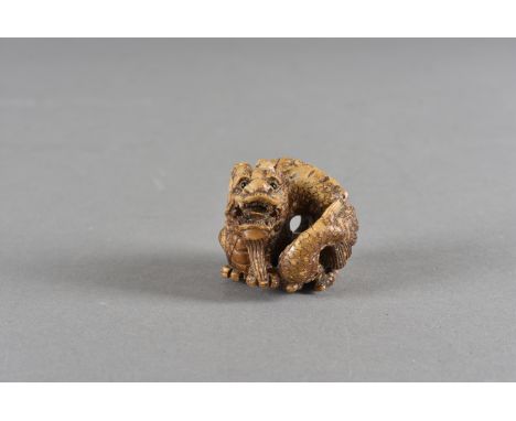 A Meiji period Japanese hardwood netsuke, the boxwood carving modelled as a curled dragon with black glass eyes 4 cm high 