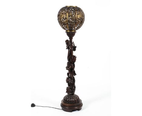 A carved wood and gilt-metal floor lamp, late 19th/early 20th century. The gilt-metal globe shaped shade pierced with chinois