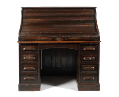 A 1940s oak roll top pedestal desk. The tambour lid enclosing a fully fitted interior, the kneehole flanked by to pull out sl