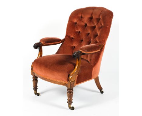 A Victorian upholstered button back arm chair. With scroll carved arms, upholstered in red/dark orange velvet, on turned balu