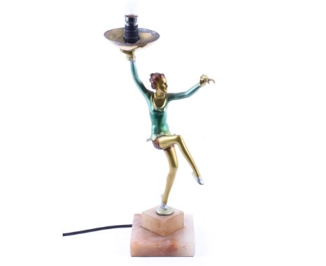 An Art Deco style dancer table lamp. The dancer supporting a lamp with opaque globe shape, she wearing a green frilled top an