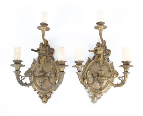 A pair of early 20th century gilt metal wall lights. Each with oval cartouche shaped wall plaque issuing three lights, the ce